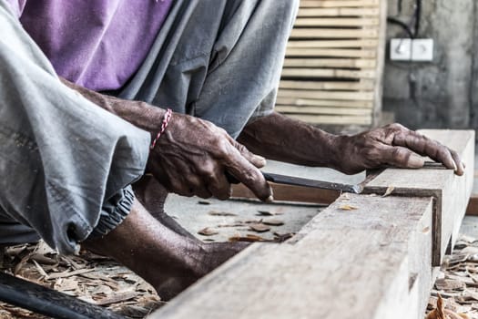 Close up of warn hands of carpenter working with manual tools in traditional carpentry shop in a third world country. Heavy labour intensive manual work.