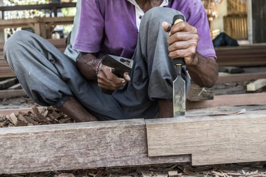 Close up of warn hands of carpenter working with manual tools in traditional carpentry shop in a third world country. Heavy labour intensive manual work.