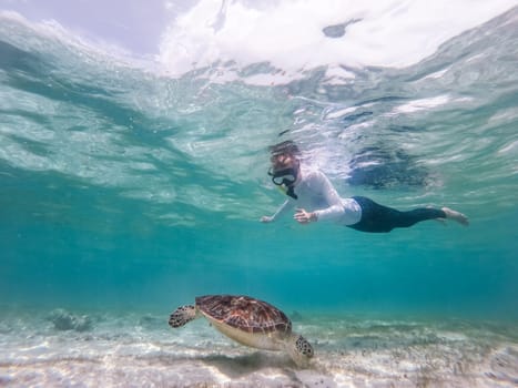 Woman wearing snokeling mask swimming with sea turtle in turquoise blue water of Gili islands, Indonesia. Underwater photo. Hawksbill sea turtle, Eretmochelys imbricata is endangered species.