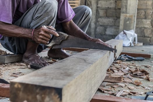 Close up of warn hands of carpenter working with manual tools in traditional carpentry shop in a third world country. Heavy labour intensive manual work.