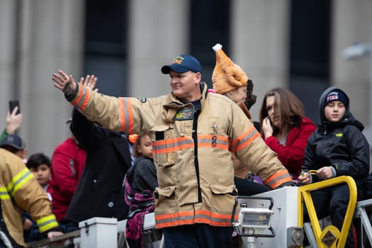 Houston, Texas, USA - November 22, 2018 The H-E-B Thanksgiving Day Parade, Firefighter on top of a firetruck waving at people