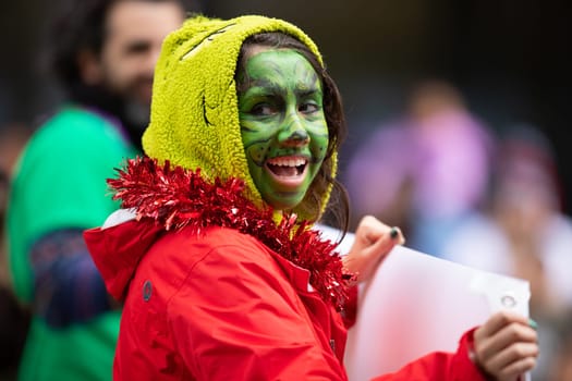 Houston, Texas, USA - November 22, 2018 The H-E-B Thanksgiving Day Parade, Woman dress up as the grinch with face paint, smiling and waving at the spectators
