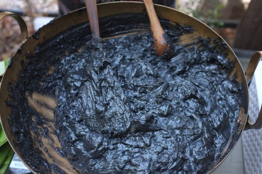 Cooking Scene of BLACK COCONUT SWEET PUDDING in Brass pot (KANOM PIAKPOON) . Thai sweetmeat