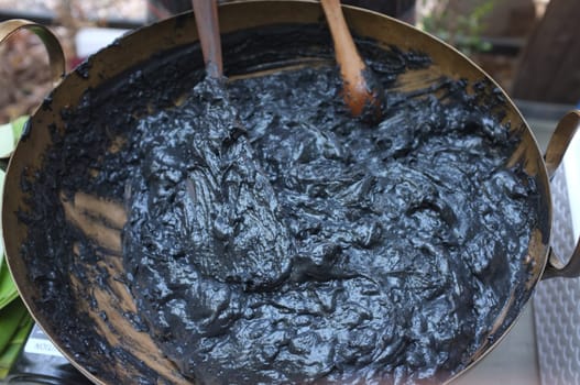 Cooking Scene of BLACK COCONUT SWEET PUDDING in Brass pot (KANOM PIAKPOON) . Thai sweetmeat