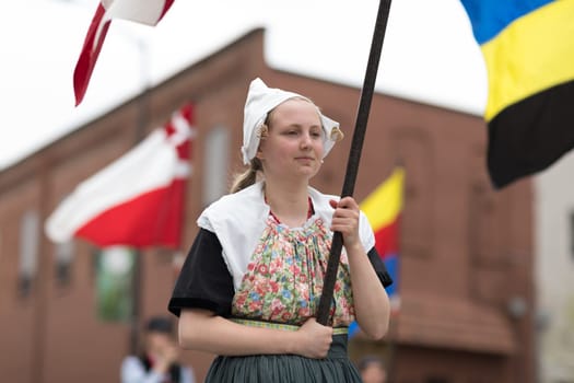 Holland, Michigan, USA - May 12, 2018 Women wearing traditional dutch clothing, carry diferent flags at the Muziek Parade, during the Tulip Time Festival