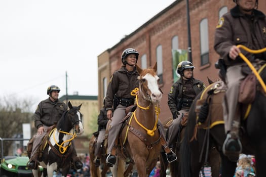 Holland, Michigan, USA - May 12, 2018 Police Officers riding horses going down the road at the Muziek Parade, during the Tulip Time Festival