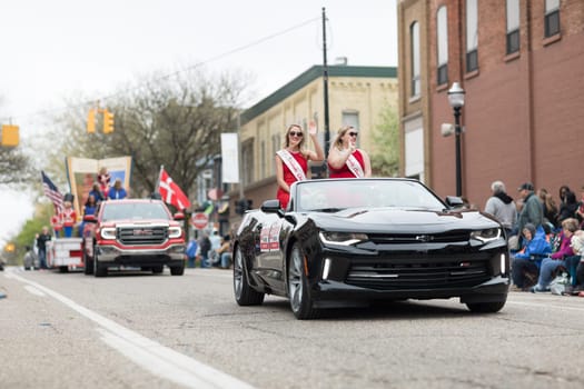 Holland, Michigan, USA - May 12, 2018 Beauty queens with ribbons that say Pulaski Queen on a car going down the road at the Muziek Parade, during the Tulip Time Festival
