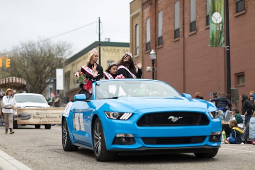 Holland, Michigan, USA - May 12, 2018 Beauty queen riding on a ford mustang wearing ribbons that say Miss Michigan at the Muziek Parade, during the Tulip Time Festival