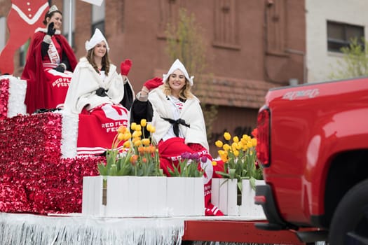 Holland, Michigan, USA - May 12, 2018 Beauty queens on a red float, going down the road at the Muziek Parade, during the Tulip Time Festival