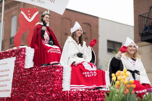 Holland, Michigan, USA - May 12, 2018 Beauty queens on a red float, going down the road at the Muziek Parade, during the Tulip Time Festival