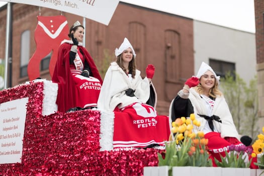 Holland, Michigan, USA - May 12, 2018 Beauty queens on a red float, going down the road at the Muziek Parade, during the Tulip Time Festival