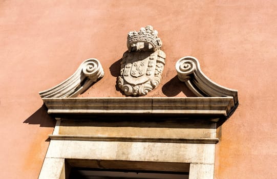 Detail of the broken pediment and royal coat of arms on top of the portal of the Church of the Flamengas in Alcantara, Lisbon, Portugal