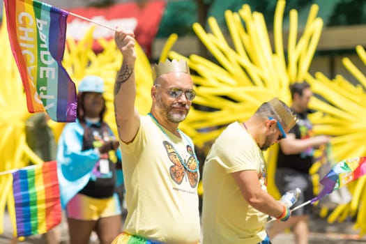 Chicago, Illinois, USA - June 24, 2018 Man wearing a crown waving the rainbow flag celebrating during the LGBTQ Pride Parade in Chicago