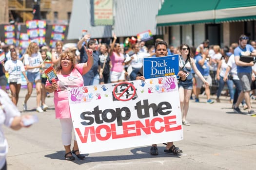 Chicago, Illinois, USA - June 24, 2018 People sign against gun violence that say, stop the violence,  during the LGBTQ Pride Parade in Chicago
