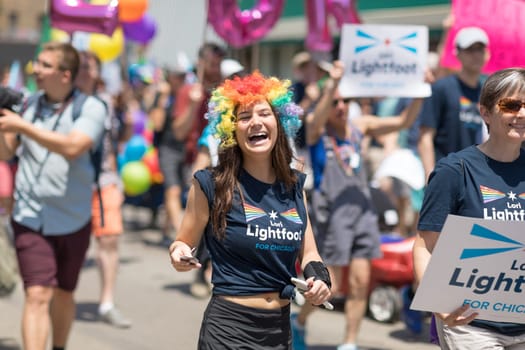 Chicago, Illinois, USA - June 24, 2018 Young woman wearing a wig with the colors of the rainbow and a shirt that promotes Lori Lightfoot for chicago during the LGBTQ Pride Parade in Chicago