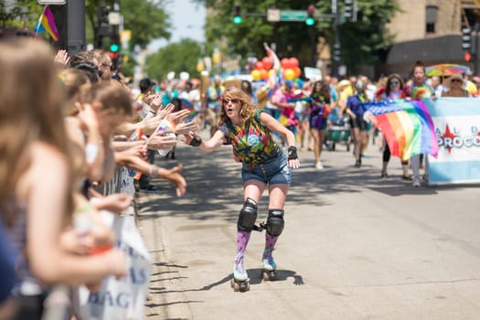 Chicago, Illinois, USA - June 24, 2018 Woman on roller skates giving the spectaors high fives during the LGBTQ Pride Parade in Chicago