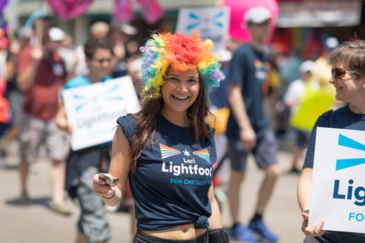 Chicago, Illinois, USA - June 24, 2018 Young woman wearing a wig with the colors of the rainbow and a shirt that promotes Lori Lightfoot for chicago during the LGBTQ Pride Parade in Chicago