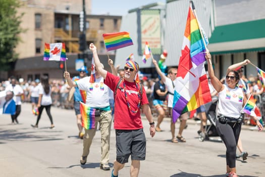 Chicago, Illinois, USA - June 24, 2018 People waving canadian flags with the rainbow colors and rainbow flags during the LGBTQ Pride Parade in Chicago