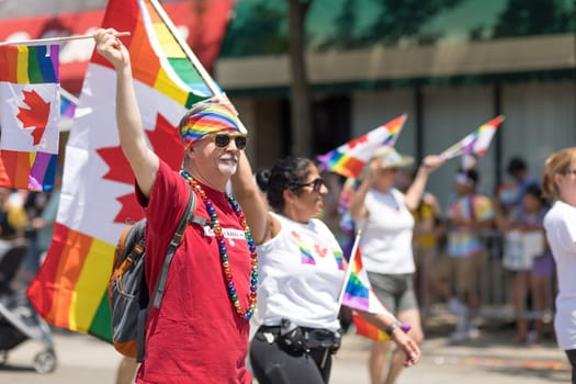 Chicago, Illinois, USA - June 24, 2018 People waving canadian flags with the rainbow colors and rainbow flags during the LGBTQ Pride Parade in Chicago
