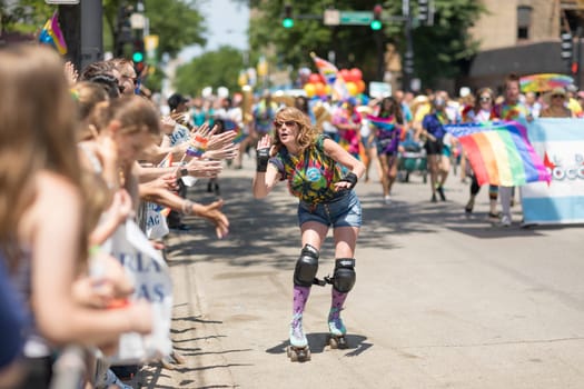 Chicago, Illinois, USA - June 24, 2018 Woman on roller skates giving the spectaors high fives during the LGBTQ Pride Parade in Chicago