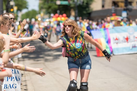 Chicago, Illinois, USA - June 24, 2018 Woman on roller skates giving the spectaors high fives during the LGBTQ Pride Parade in Chicago