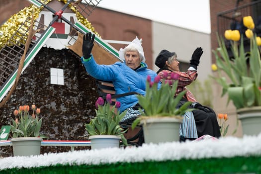 Holland, Michigan, USA - May 12, 2018 Older women wearing traditional dutch clothing wave at the spectators at the Muziek Parade, during the Tulip Time Festival