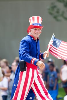 Washington, D.C., USA - July 4, 2018, The National Independence Day Parade, Man dress as Uncle Sam, waving the american flag, going down constitution avenue