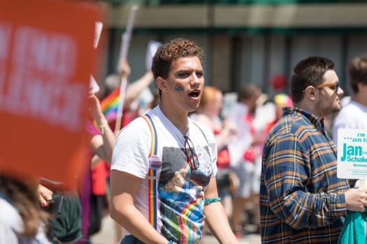 Chicago, Illinois, USA - June 24, 2018  Man wearing a rainbow sticker on his face walks down the street during the LGBTQ Pride Parade in Chicago
