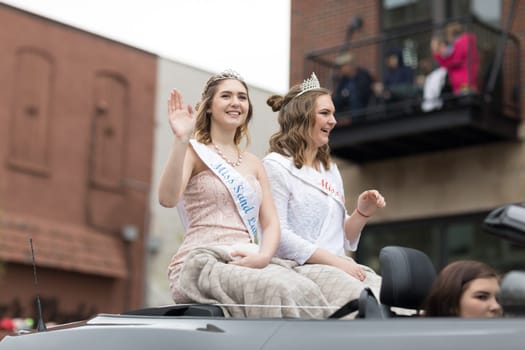 Holland, Michigan, USA - May 12, 2018 Beauty queens Miss sand lake, on top of a car going down the road at the Muziek Parade, during the Tulip Time Festival