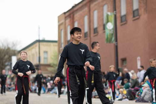 Holland, Michigan, USA - May 12, 2018 Young asian man wearing martial arts outfit walking down the road at the Muziek Parade, during the Tulip Time Festival