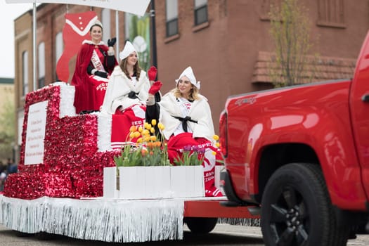 Holland, Michigan, USA - May 12, 2018 Beauty queens on a red float, going down the road at the Muziek Parade, during the Tulip Time Festival