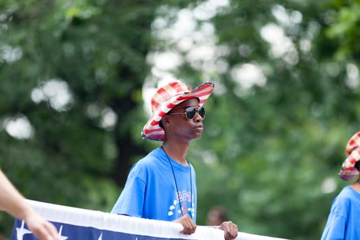 Washington, D.C., USA - July 4, 2018, young man holding a banner and wearing a hat with the colors of the american flag at the National Independence Day Parade