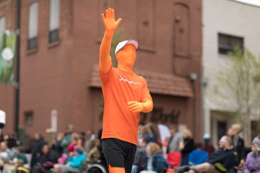 Holland, Michigan, USA - May 12, 2018 Man wearing a full orange full body suit promoting Orangetheory fitness at the Muziek Parade, during the Tulip Time Festival