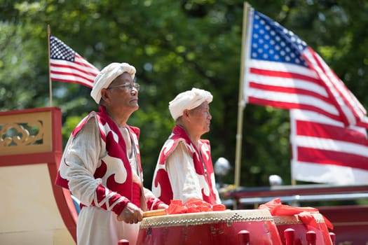 Washington, D.C., USA - July 4, 2018, The National Independence Day Parade, Chinese, wearing traditional clothing, playing drums, and with american flags, going down constitution avenue during the parade
