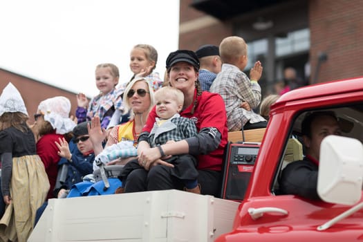 Holland, Michigan, USA - May 12, 2018 People wearing traditional dutch clothing riding a classic chevrolet truck going down the road at the Muziek Parade, during the Tulip Time Festival