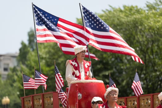 Washington, D.C., USA - July 4, 2018, The National Independence Day Parade, Chinese, wearing traditional clothing, playing drums, and with american flags, going down constitution avenue during the parade