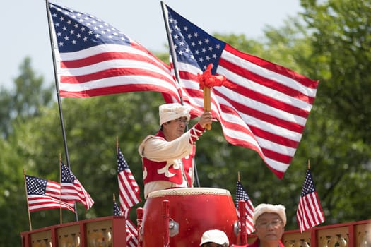 Washington, D.C., USA - July 4, 2018, The National Independence Day Parade, Chinese, wearing traditional clothing, playing drums, and with american flags, going down constitution avenue during the parade