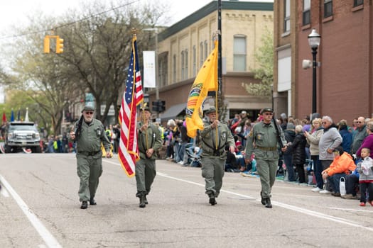 Holland, Michigan, USA - May 12, 2018 Men wearing military uniforms carry wepons and the american flag at the Muziek Parade, during the Tulip Time Festival