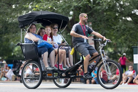 Washington, D.C., USA - July 4, 2018, Members of a family travel the streets on a tricycle prior the National Independence Day Parade
