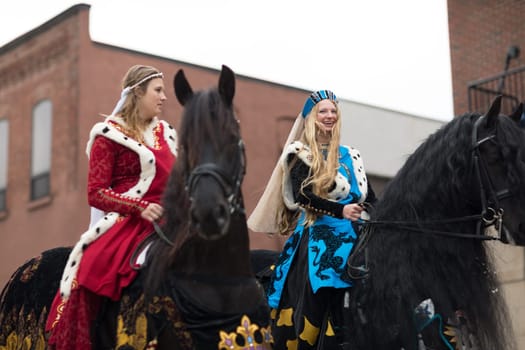 Holland, Michigan, USA - May 12, 2018 women wearing medieval clothing riding horses going down the road at the Muziek Parade, during the Tulip Time Festival