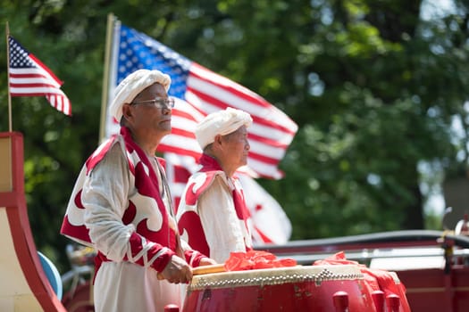 Washington, D.C., USA - July 4, 2018, The National Independence Day Parade, Chinese, wearing traditional clothing, playing drums, and with american flags, going down constitution avenue during the parade
