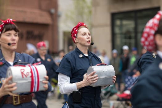 Holland, Michigan, USA - May 12, 2018 Women dress up as Rosie sing and dance at the Muziek Parade, during the Tulip Time Festival