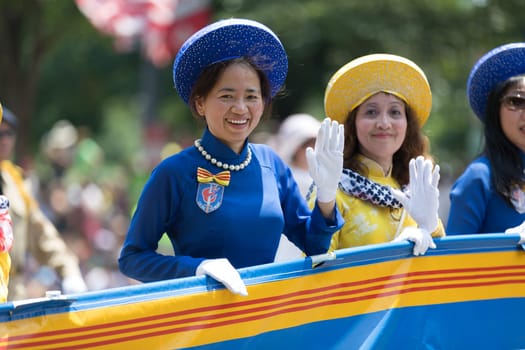 Washington, D.C., USA - July 4, 2018, The National Independence Day Parade, Vietnamese American women wearing traditional dresses, going down constitution avenue