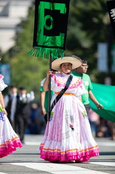 Washington, D.C., USA - September 29, 2018: The Fiesta DC Parade, Woman wearing traditional clothing from Mexico carrying a banner