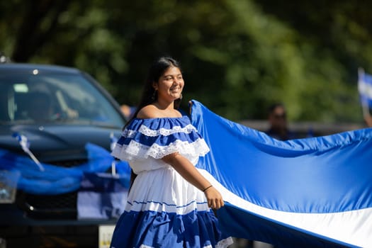 Washington, D.C., USA - September 29, 2018: The Fiesta DC Parade, Woman from el salvador wearing traditional clothing holding a large Salvadoran Flag