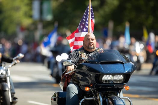 Washington, D.C., USA - September 29, 2018: The Fiesta DC Parade, Man from el Puerto Rico riding a motorcycle carrying the american flag Members of the latin american motorcycle association