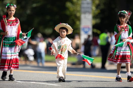 Washington, D.C., USA - September 29, 2018: The Fiesta DC Parade, Boy and girl wearing traditional clothing carrying roses and mexican flags