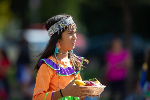 Washington, D.C., USA - September 29, 2018: The Fiesta DC Parade, peruvian girl wearing traditional clothing walking down the street carrying friut