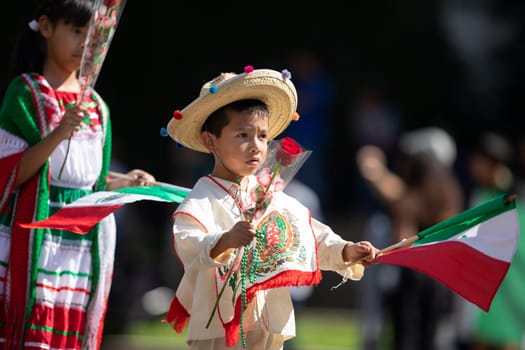 Washington, D.C., USA - September 29, 2018: The Fiesta DC Parade, Boy and girl wearing traditional clothing carrying roses and mexican flags