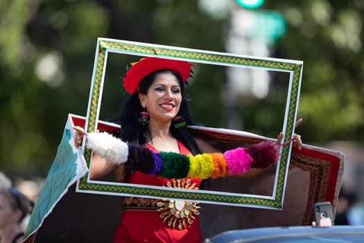 Washington, D.C., USA - September 29, 2018: The Fiesta DC Parade, Peruvian woman wearing traditional clothing holding a frame poses for the camera